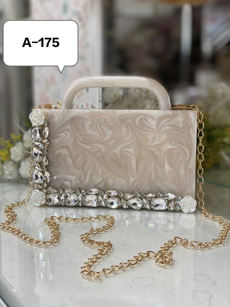 a white clutch with a gold chain and diamonds